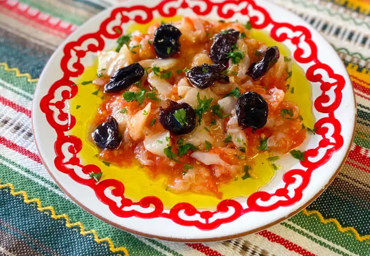 Plato con bacalao desmigado, aceitunas negras y perejil, bañado en aceite de oliva. Una de las muchas recetas de bacalao.