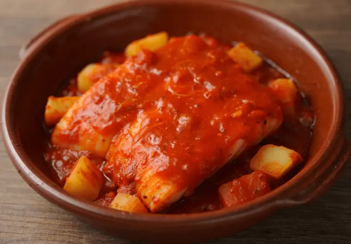 Bacalao a la riojana, un plato tradicional con trozos de patata y pimiento en una rica salsa de tomate.