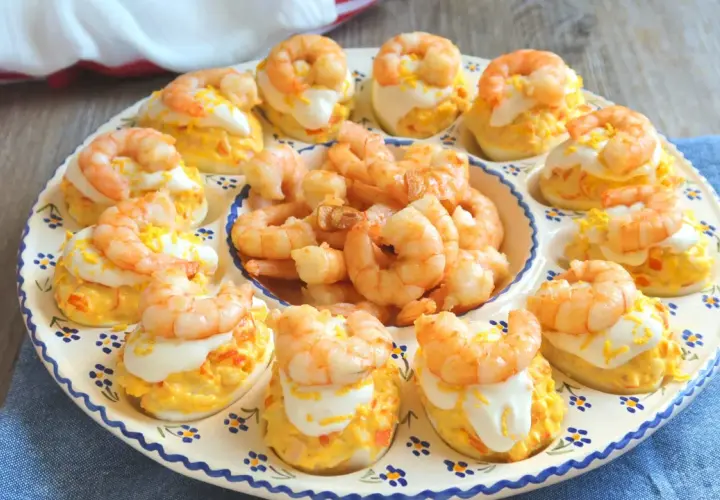 Huevos rellenos decorados con gambas y una pizca de ralladura de huevo. Un aperitivo delicioso y vistoso.