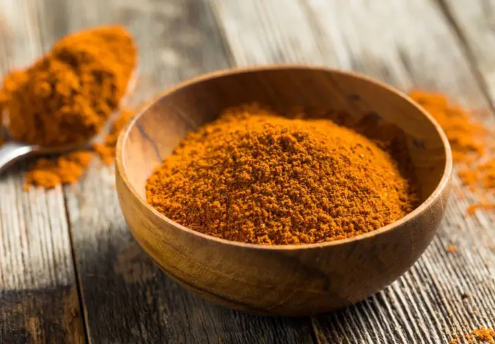 Especias anaranjadas en un cuenco de madera, perfectas para aprender como hacer ras el hanout.