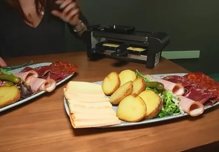 Platos con patatas, embutidos y queso listos para preparar deliciosas recetas raclette en la parrilla.