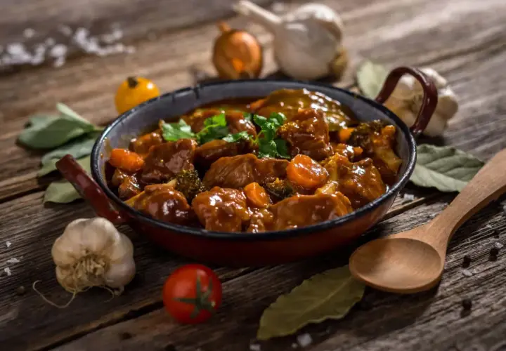 Un delicioso ragú de carne con zanahorias y brócoli en una sartén, acompañado de ajo, cebolla y hierbas.