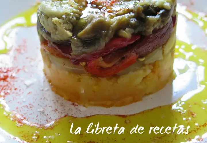 Timbal de escalivada, un plato de verduras asadas en capas, con pimientos rojos y berenjena, servido con aceite de oliva y pimentón.