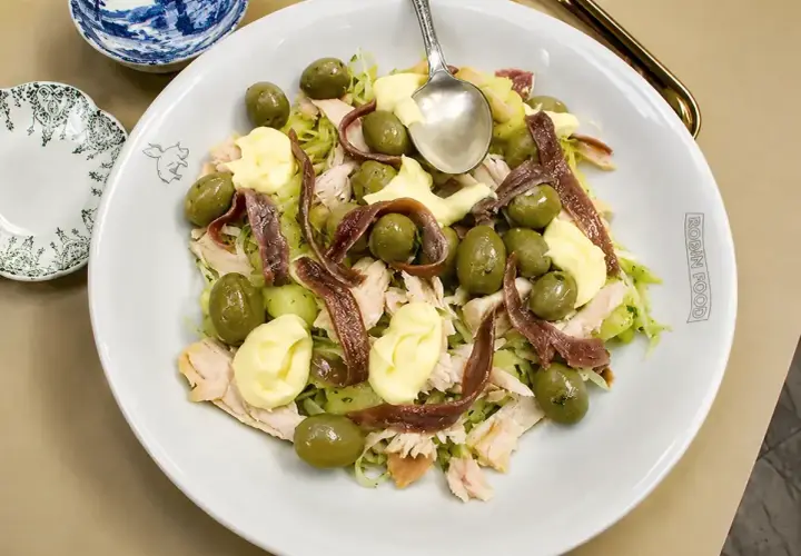 Ensalada fresca con patatas, aceitunas verdes, mayonesa y tiras de anchoas.