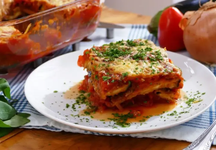 Una porción de parmigiana que es un delicioso plato de berenjenas, salsa de tomate y queso, espolvoreado con perejil fresco.