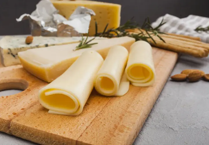 Variedad de quesos, incluyendo uno azul y rollos de queso amarillo. ¡Cuidado, el queso tiene lactosa!