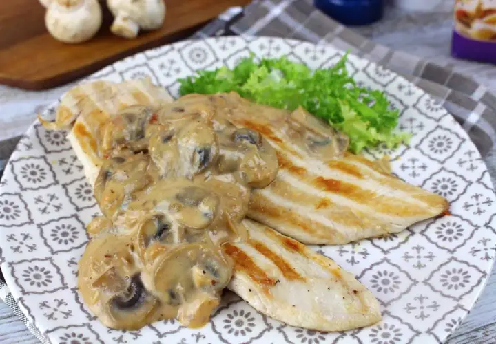 Pechugas de pollo a la parrilla cubiertas con una cremosa salsa de champiñones, servidas con lechuga fresca.