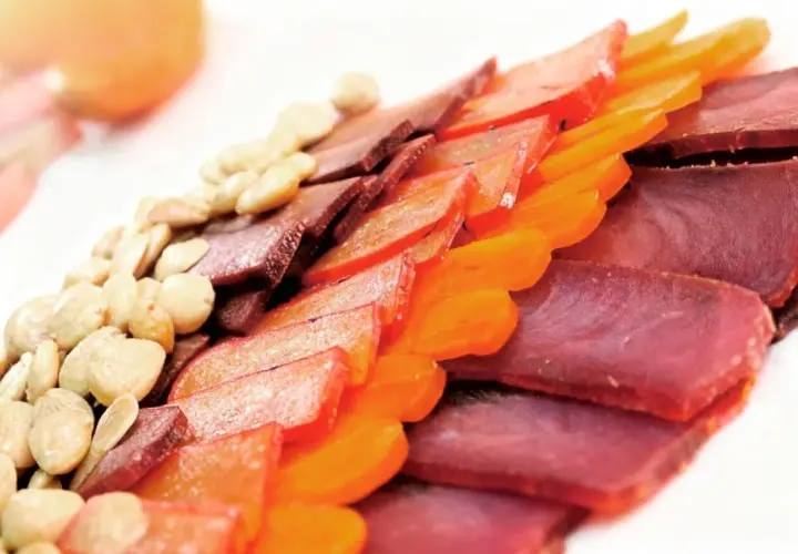 Finas lonchas de carne curada, como la mohama, junto a frutos secos y trozos de fruta deshidratada, crean un plato colorido y apetitoso.