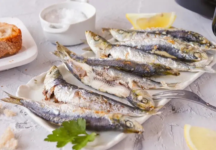 Sardinas empanadas, doradas y crujientes, servidas con limón y pan. Un plato delicioso y saludable.