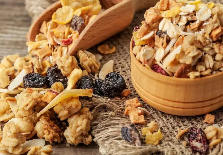Un tazón de madera lleno de muesli, una mezcla de avena, frutos secos y cereales. El muesli es un desayuno saludable y energético.