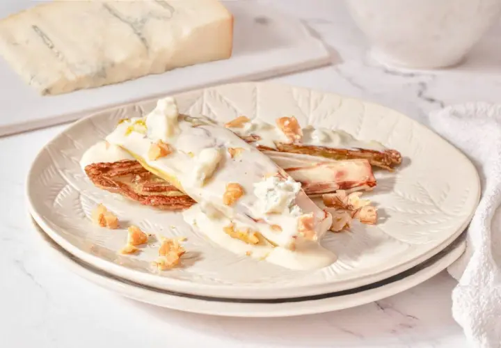 Endivias gratinadas con salsa cremosa, trozos de gorgonzola y nueces crujientes.