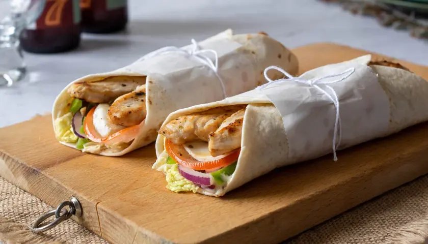 Dos deliciosos wraps de pollo a la parrilla, rellenos de vegetales frescos y queso, listos para disfrutar.