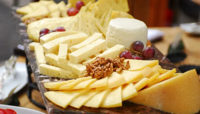 Tabla de quesos variados, cortados en diferentes formas para una presentación ideal. Aprende como cortar quesos para tablas y disfruta de esta delicia.