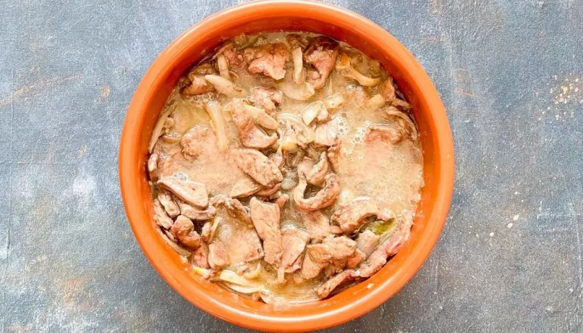 Un plato de barro con un delicioso hígado encebollado, jugoso y lleno de sabor.