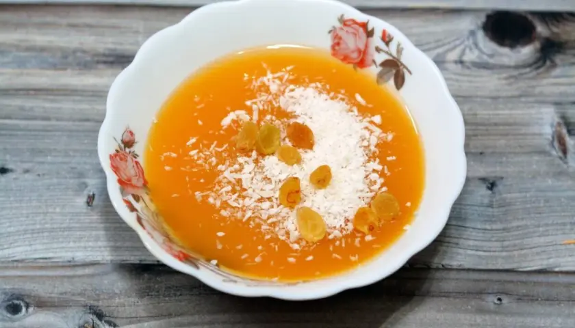 Un postre naranja con coco rallado y pasas, quizás hecho con fécula.