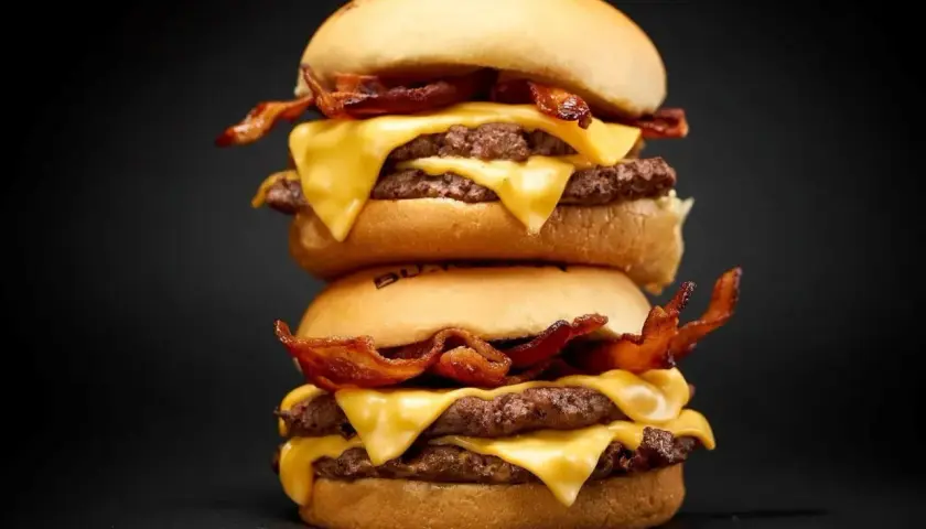 Dos hamburguesas apiladas con queso derretido y tocino crujiente. ¡Una guía visual de como cocinar hamburguesas perfectas!