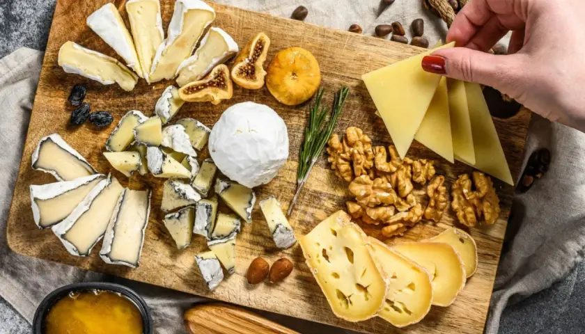 Tabla de quesos variados, incluyendo queso brie con que se acompaña de miel, higos secos, nueces y almendras.