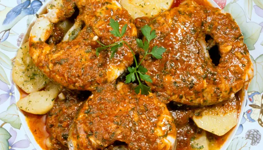 Merluza a la gallega, jugosa y sabrosa, servida con patatas y perejil fresco.