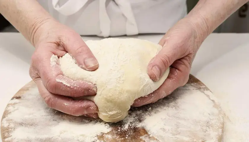 Manos amasando masa con harina, preparando diferentes tipos de levadura para panadería.