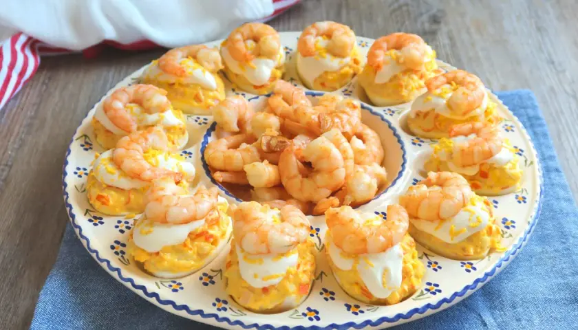 Huevos rellenos decorados con gambas y una pizca de ralladura de huevo. Un aperitivo delicioso y vistoso.