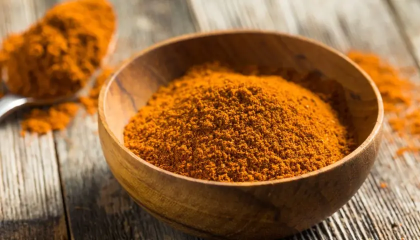 Especias anaranjadas en un cuenco de madera, perfectas para aprender como hacer ras el hanout.
