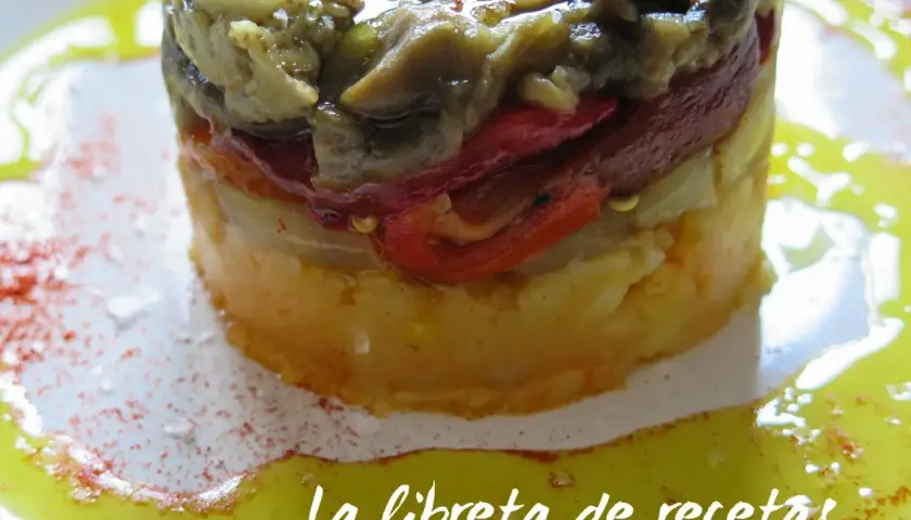 Timbal de escalivada, un plato de verduras asadas en capas, con pimientos rojos y berenjena, servido con aceite de oliva y pimentón.