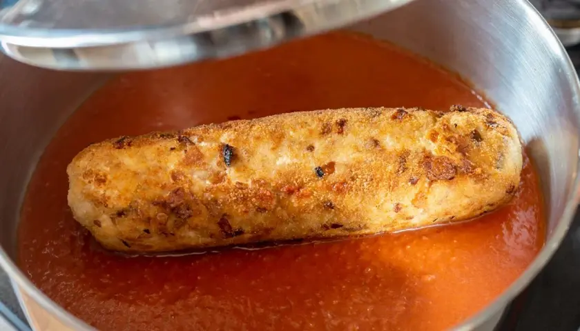 Rollo de bonito dorado y crujiente nadando en una salsa de tomate casera, listo para ser servido.
