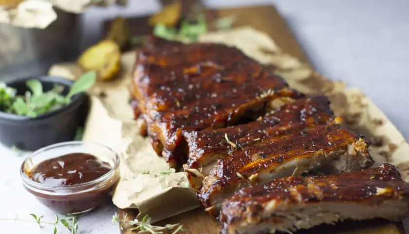 Costillas de cerdo al horno, jugosas y glaseadas, servidas con salsa barbacoa y hierbas frescas. ¡Un festín irresistible!