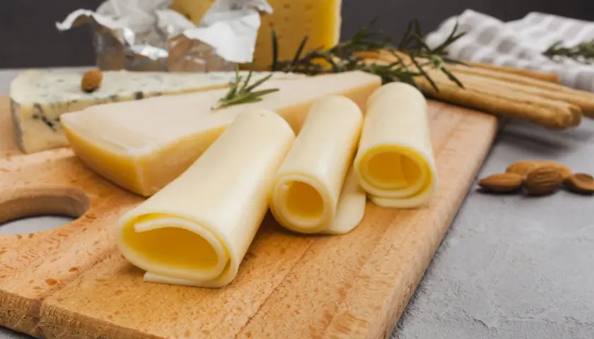 Variedad de quesos, incluyendo uno azul y rollos de queso amarillo. ¡Cuidado, el queso tiene lactosa!
