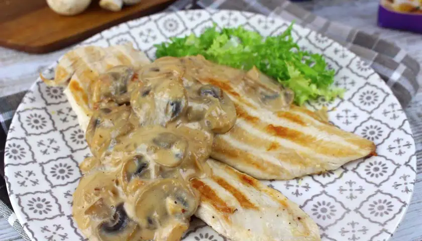 Pechugas de pollo a la parrilla cubiertas con una cremosa salsa de champiñones, servidas con lechuga fresca.