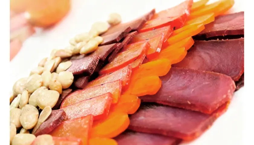 Finas lonchas de carne curada, como la mohama, junto a frutos secos y trozos de fruta deshidratada, crean un plato colorido y apetitoso.