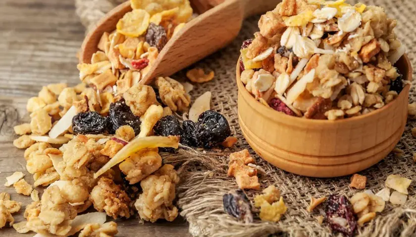 Un tazón de madera lleno de muesli, una mezcla de avena, frutos secos y cereales. El muesli es un desayuno saludable y energético.