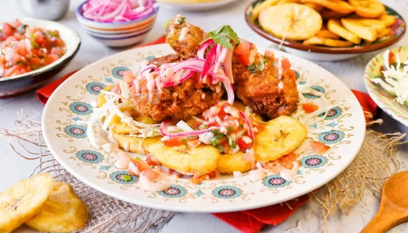 Pollo chuco crujiente con plátanos fritos, pico de gallo y cebolla morada encurtida. ¡Un festín de sabores!