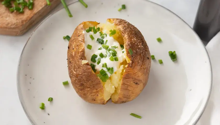 Patatas asadas crujientes rellenas de crema agria y cebollino fresco. Un plato sencillo y delicioso.