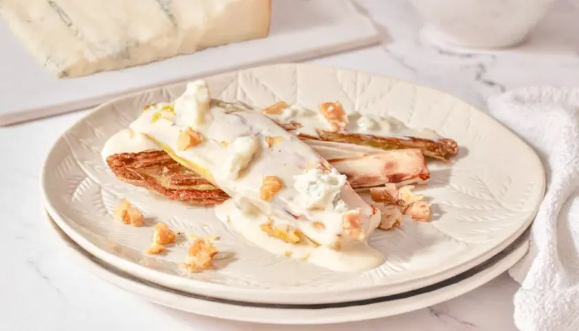 Endivias gratinadas con salsa cremosa, trozos de gorgonzola y nueces crujientes.