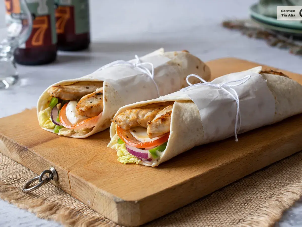 Dos deliciosos wraps de pollo a la parrilla, rellenos de vegetales frescos y queso, listos para disfrutar.