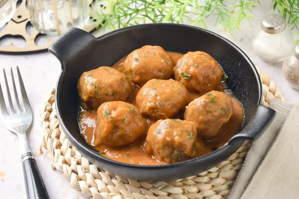 Deliciosas albóndigas caseras en salsa, perfectas para tu próxima receta. Servidas en un cuenco negro con un tenedor al lado.