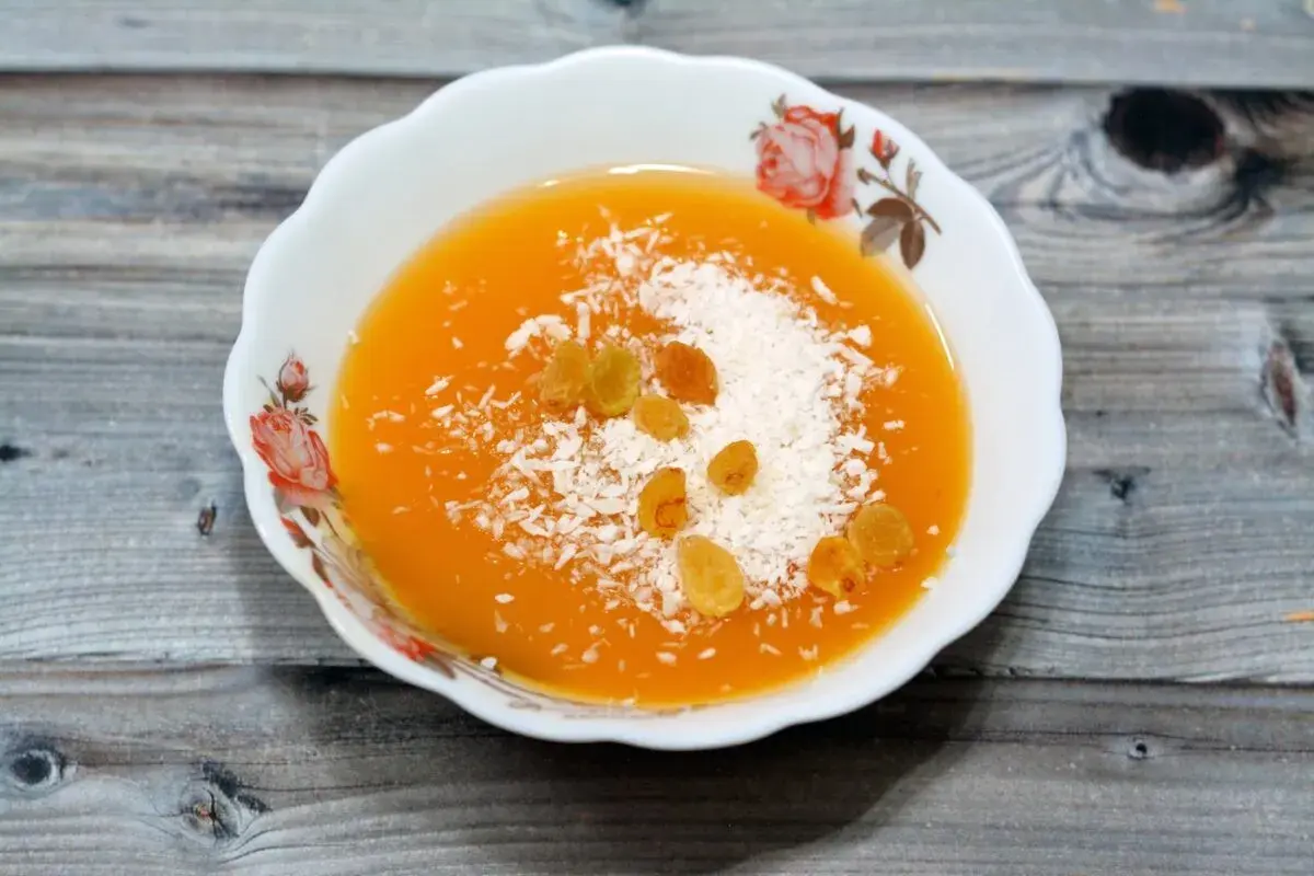 Un postre naranja con coco rallado y pasas, quizás hecho con fécula.
