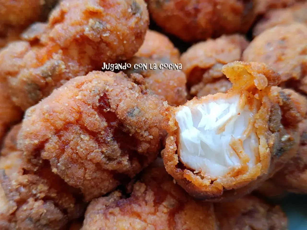Trozos dorados y crujientes de cazon en adobo, listos para disfrutar. Uno muestra su interior blanco y tierno.
