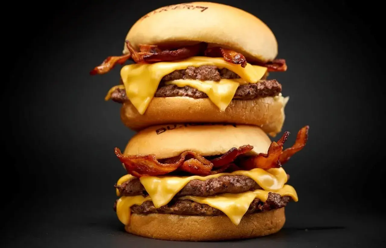 Dos hamburguesas apiladas con queso derretido y tocino crujiente. ¡Una guía visual de como cocinar hamburguesas perfectas!