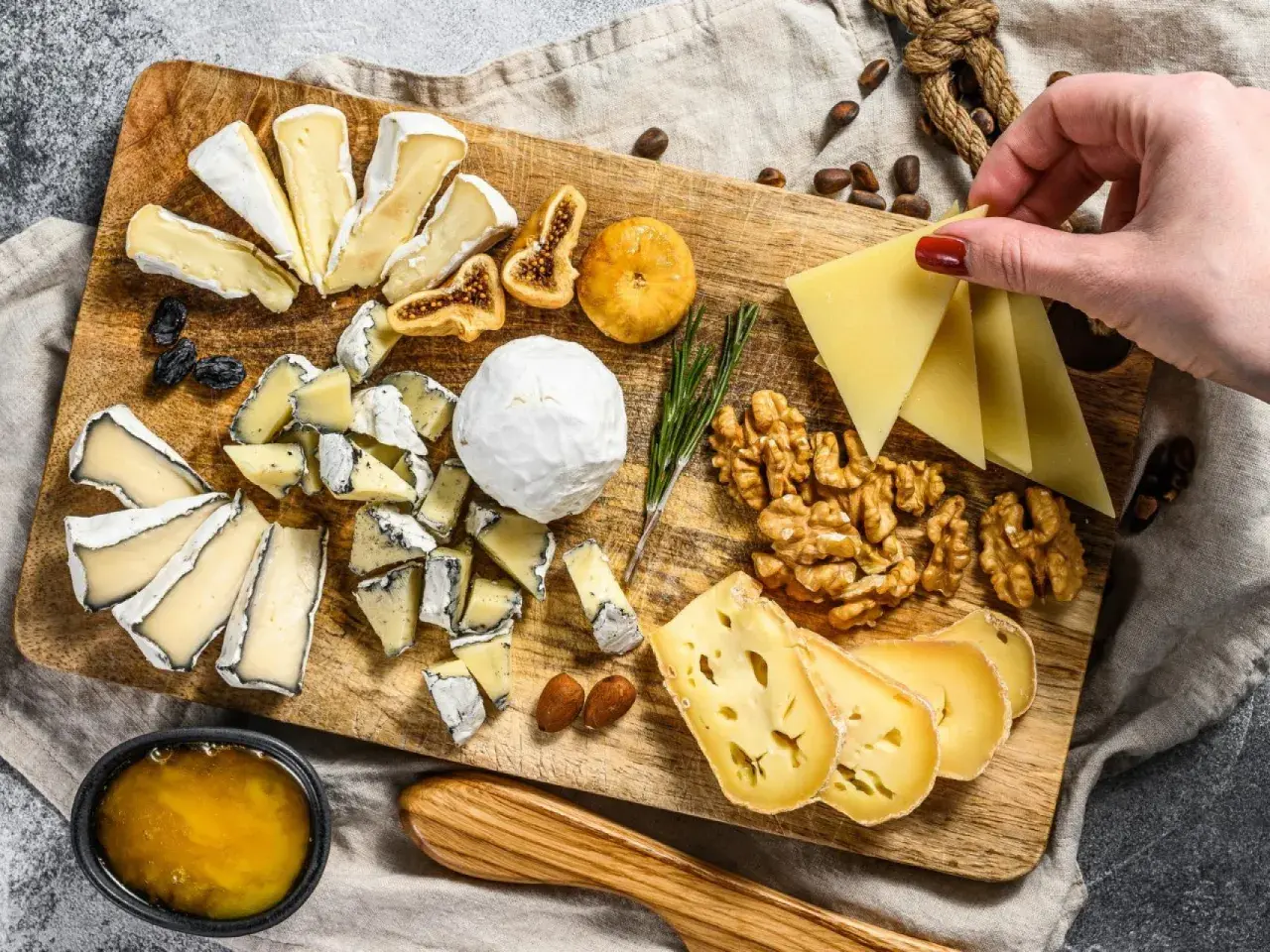 Tabla de quesos variados, incluyendo queso brie con que se acompaña de miel, higos secos, nueces y almendras.
