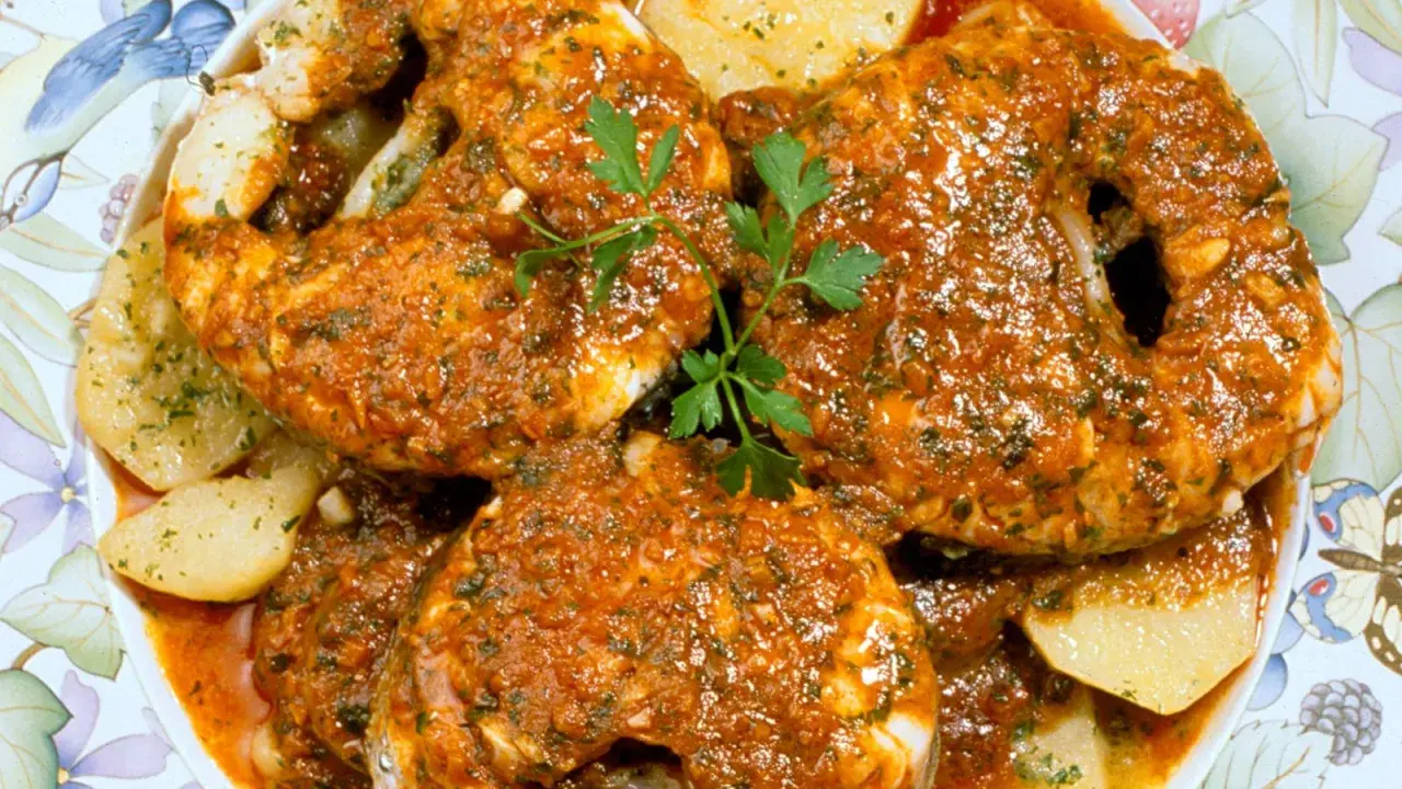 Merluza a la gallega, jugosa y sabrosa, servida con patatas y perejil fresco.