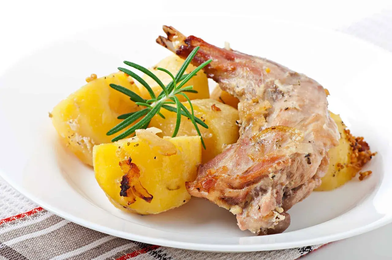 Conejo al horno jugoso con patatas asadas y romero fresco. Un plato tradicional y delicioso.