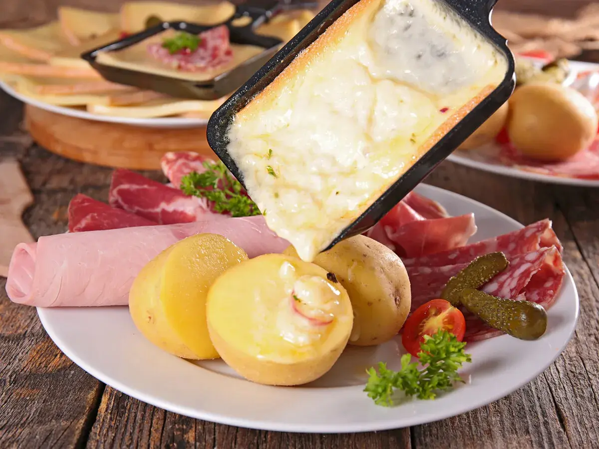 Raclette, comida típica de Suiza, con queso derretido, patatas, embutidos y pepinillos.