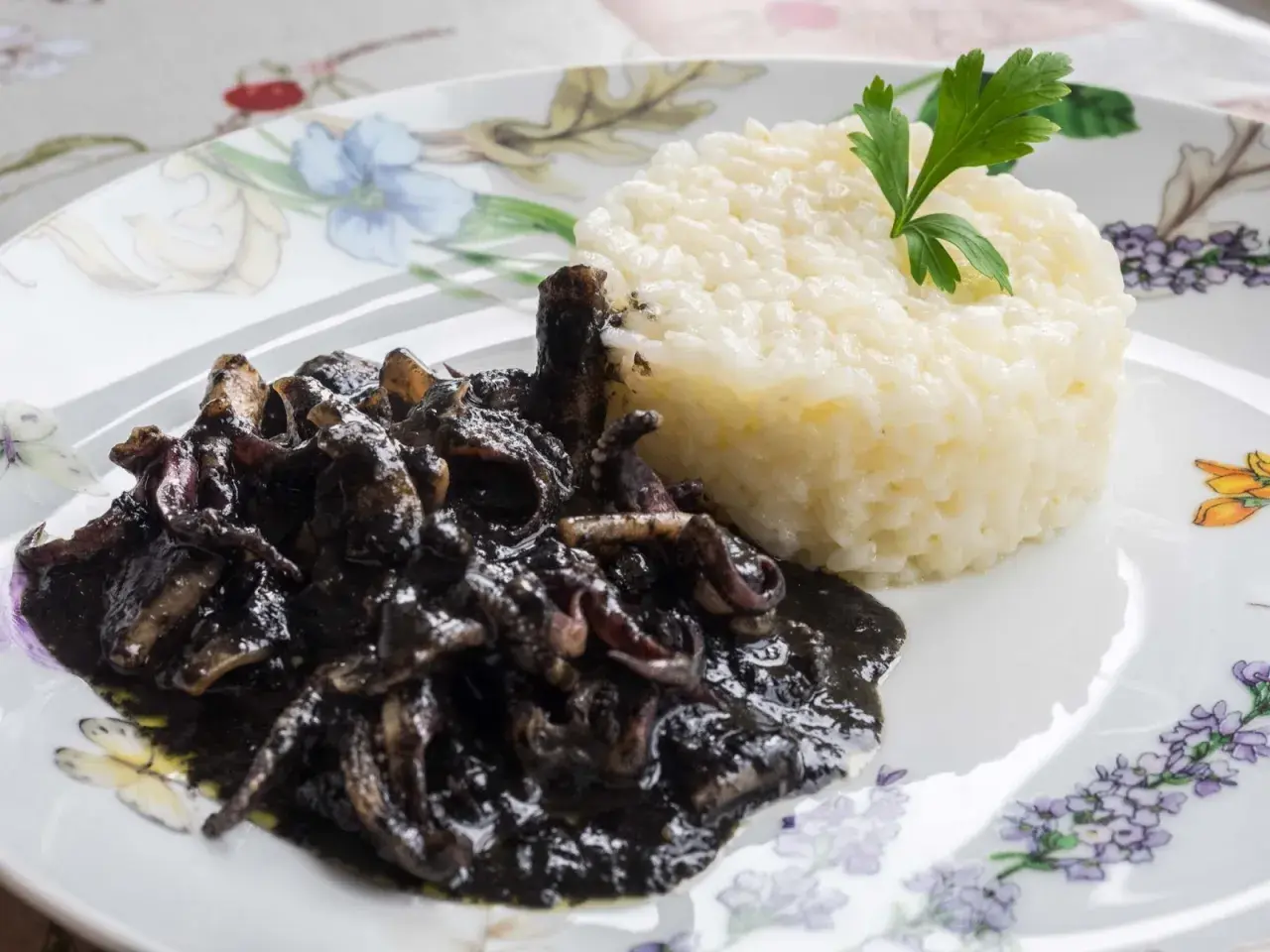 Deliciosos calamares en su tinta, servidos con arroz blanco y decorados con perejil fresco.
