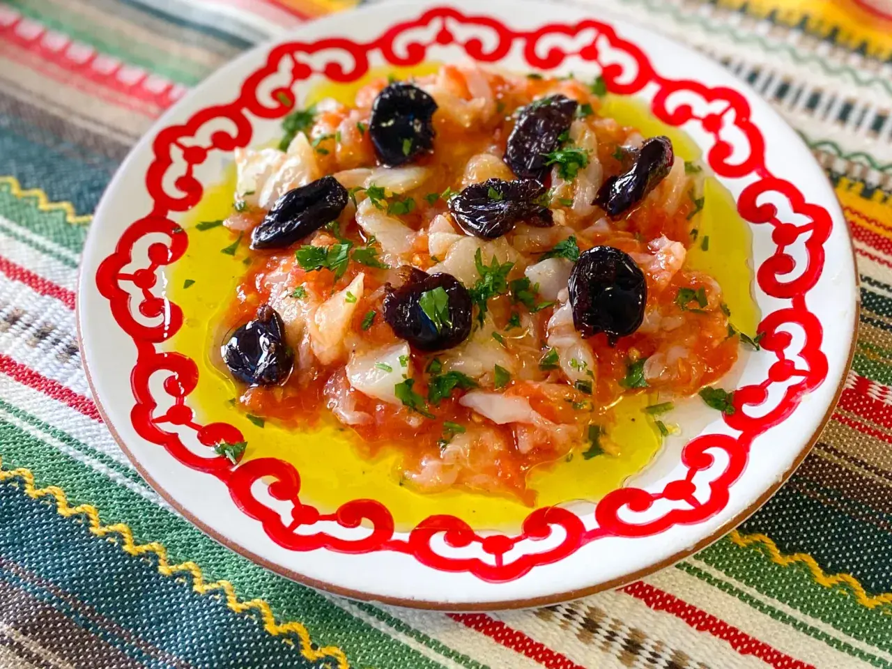 Plato con bacalao desmigado, aceitunas negras y perejil, bañado en aceite de oliva. Una de las muchas recetas de bacalao.