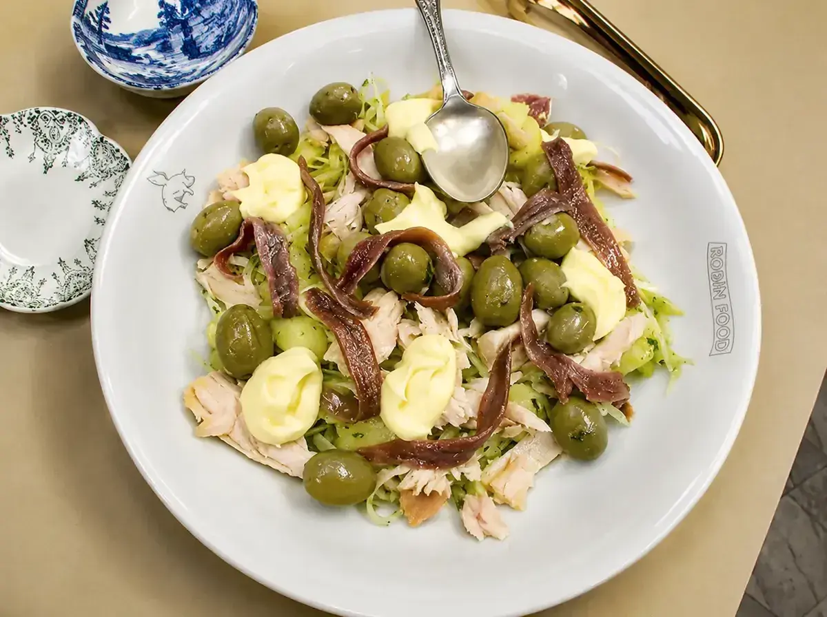 Ensalada fresca con patatas, aceitunas verdes, mayonesa y tiras de anchoas.