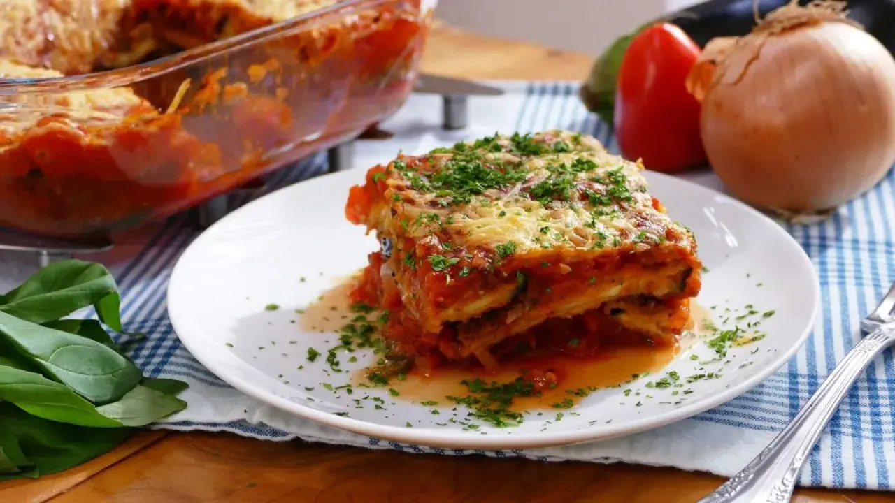Una porción de parmigiana que es un delicioso plato de berenjenas, salsa de tomate y queso, espolvoreado con perejil fresco.