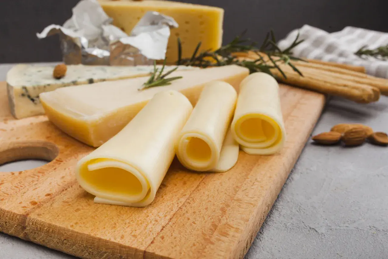 Variedad de quesos, incluyendo uno azul y rollos de queso amarillo. ¡Cuidado, el queso tiene lactosa!
