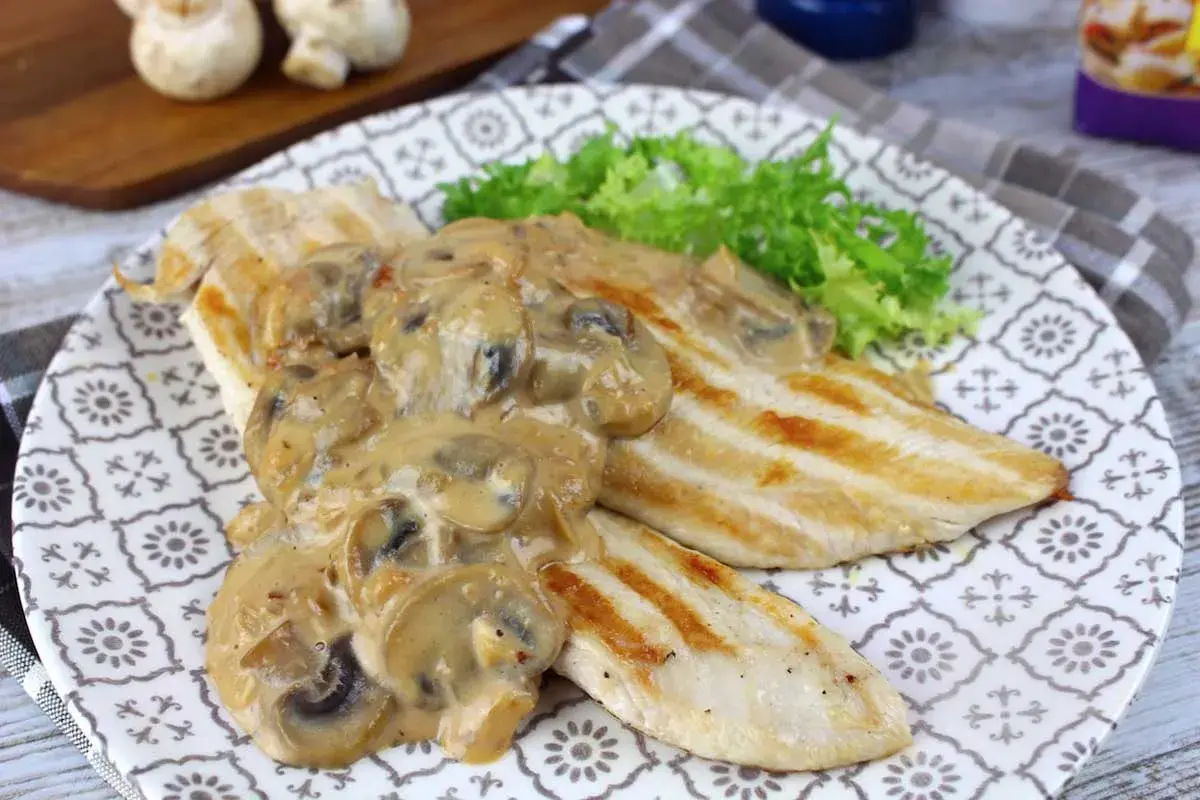 Pechugas de pollo a la parrilla cubiertas con una cremosa salsa de champiñones, servidas con lechuga fresca.